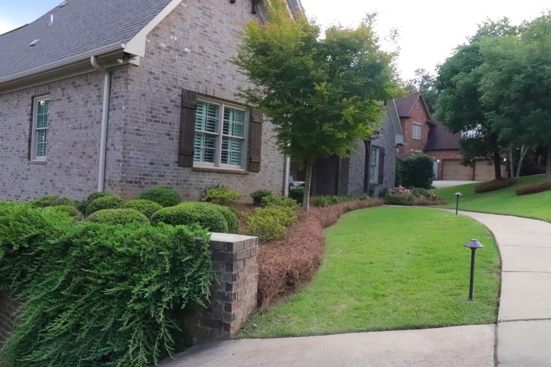 Elegant brick house with manicured landscaping and a walkway leading to the entrance.