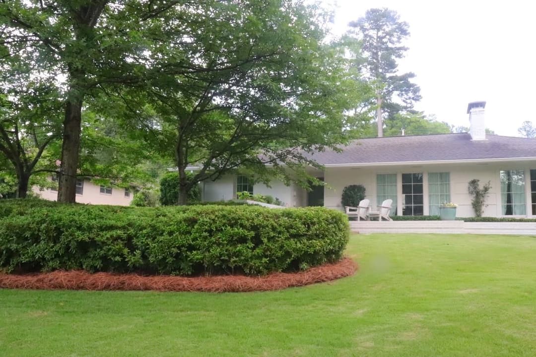Modern home with lush green landscaping and decorative shrubbery in a tranquil setting.